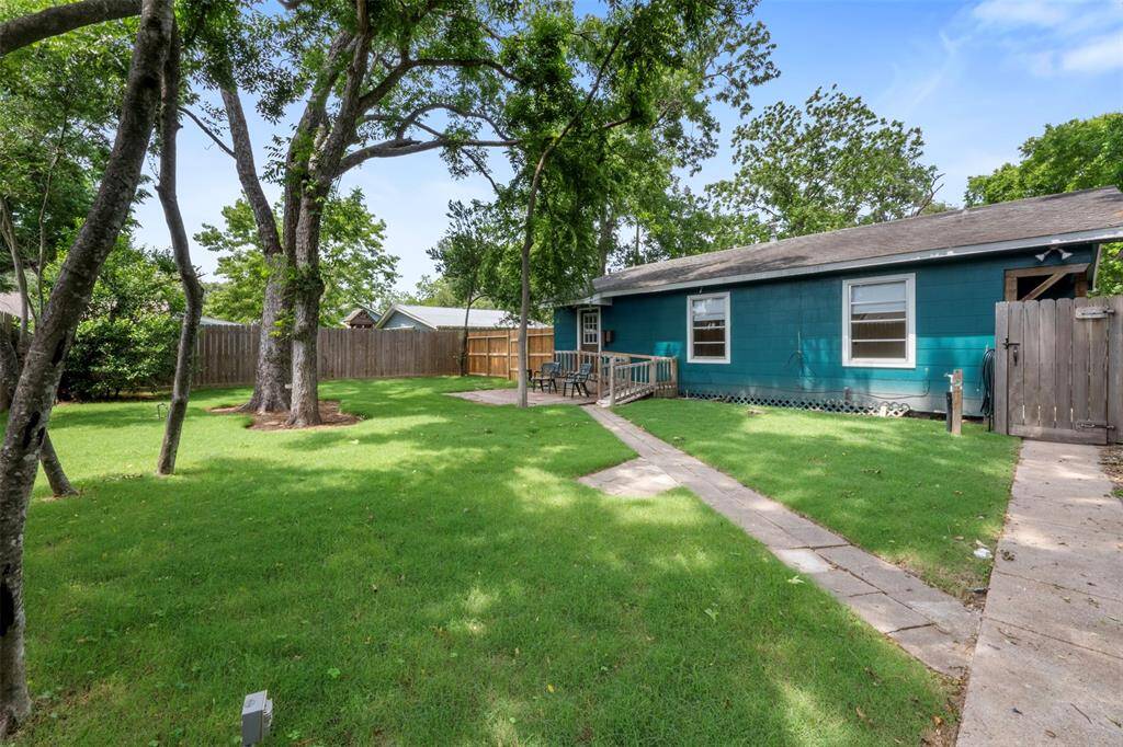 Expansive lawn space with privacy fencing and a quaint path leading to the back entrance.