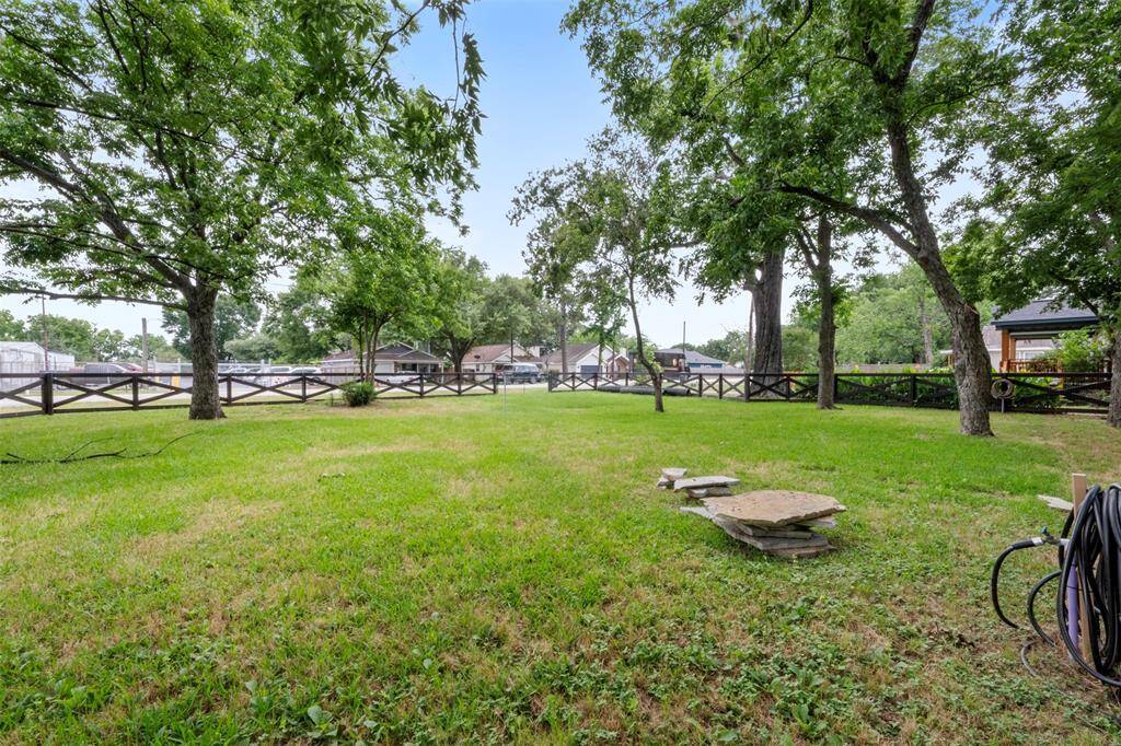 Expansive side yard with mature trees and rustic fencing offering a peaceful, open view.