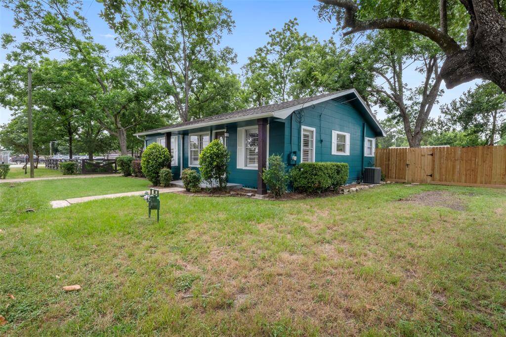 Side view of the home showcasing the fully fenced backyard and manicured landscaping.
