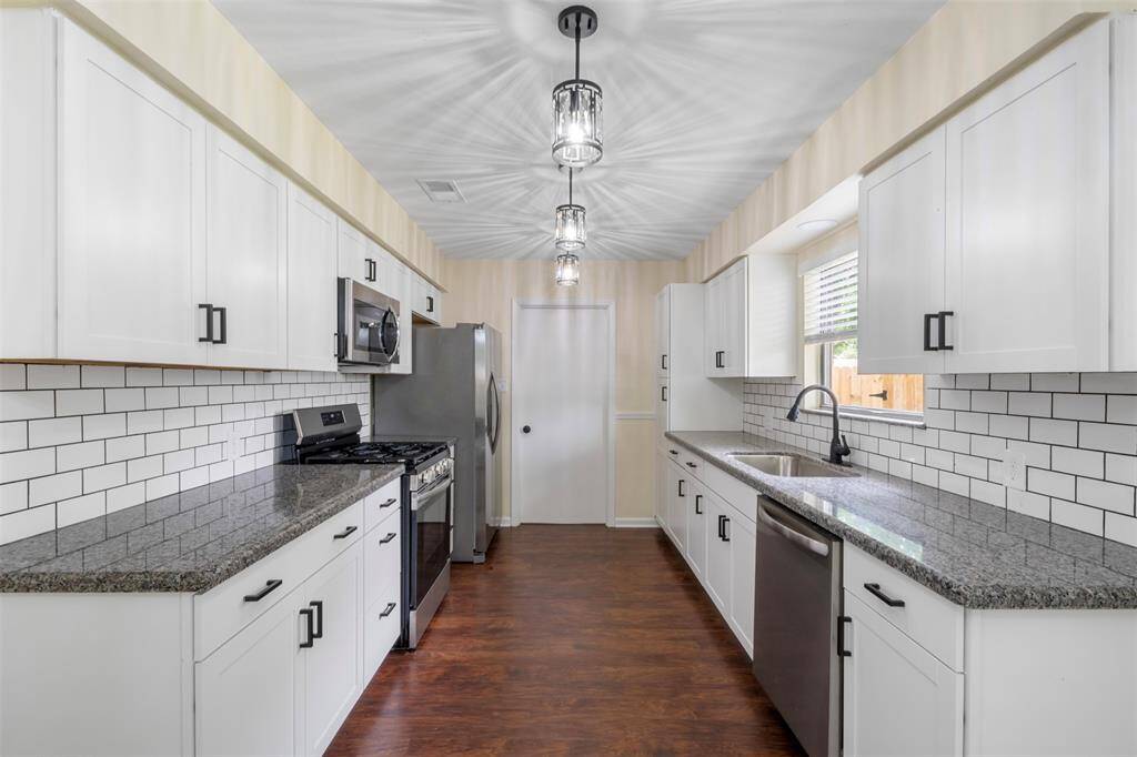 Bright galley kitchen with ample cabinetry and modern lighting.