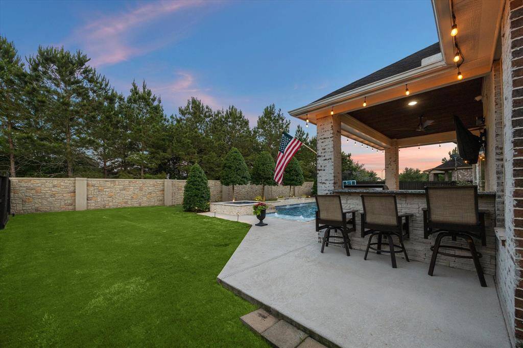 Step outside to this lovely covered patio with tongue and groove stained ceilings, schmear brick, outdoor kitchen equipped with a gas grill, bar, and a smoker ledge