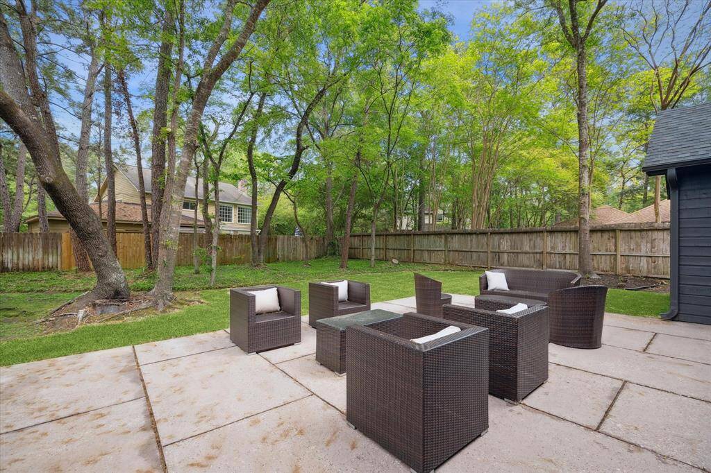 This photo showcases a spacious backyard with a patio.  The area is surrounded by a wooden fence and mature trees, providing a serene and private atmosphere.