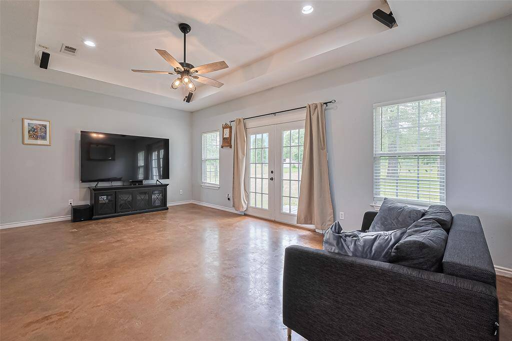 With sleek concrete floors and a tray ceiling adorned with a fan, the living room balances modern design with comfort.