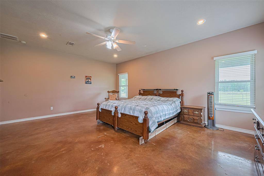 The polished concrete floors of the primary bedroom reflect the light beautifully, adding modern character and low-maintenance appeal to the expansive space.