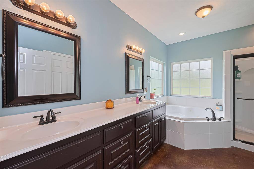 This view captures the full en suite design—tub at the center, vanity to one side, and the shower on the other—all tied together with cohesive lighting and elegant finishes.