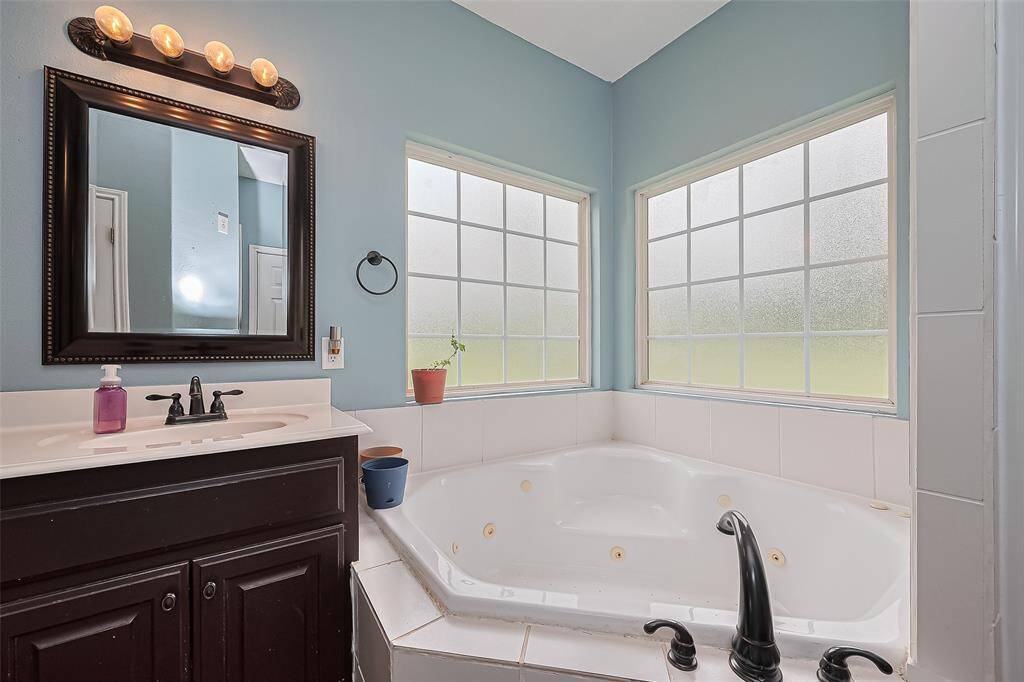 A large tub in the primary en suite sits beneath twin frosted windows, offering both privacy and natural light—perfect for a relaxing soak after a long day.