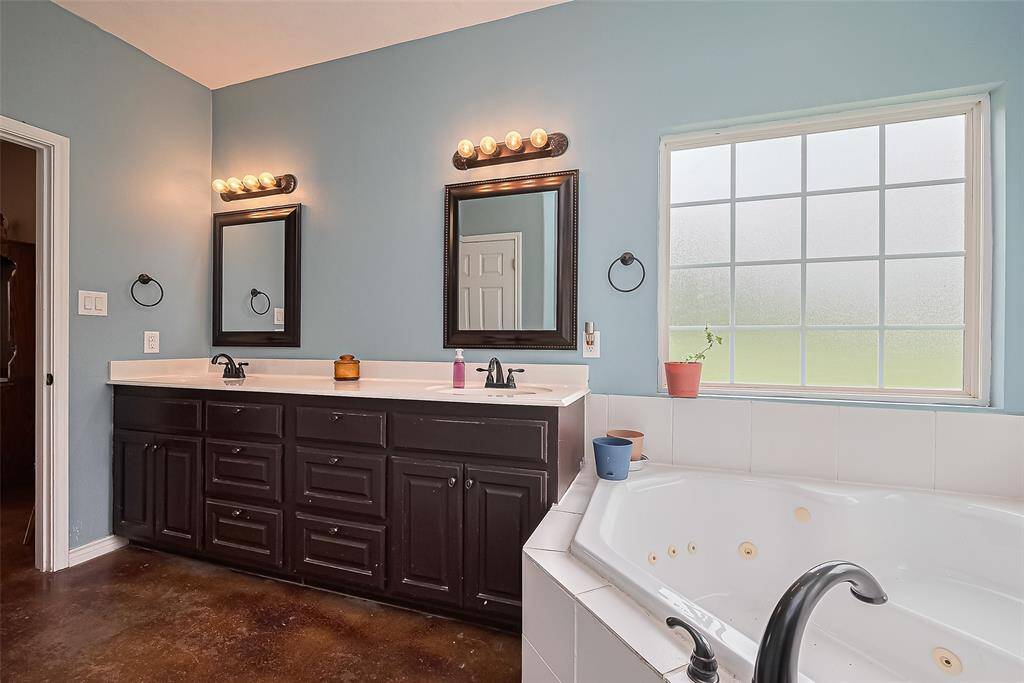 The dual-sink vanity features framed mirrors and matching cabinetry, with soft lighting that warms the space.