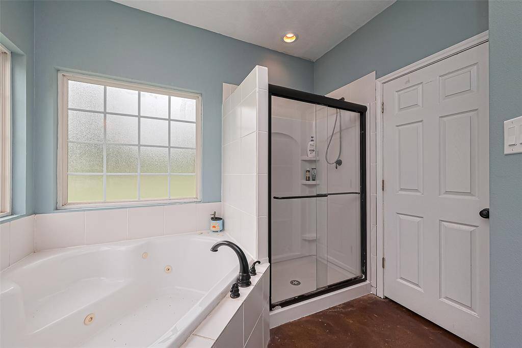 An enclosed glass shower sits neatly beside the tub, completing the en suite with clean lines and efficient layout.