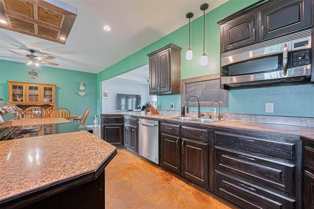 Rich-toned cabinetry provides ample storage in the kitchen, while pendant and recessed lighting create a layered, inviting atmosphere.