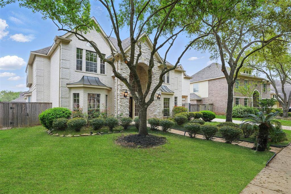 Elegant and inviting, this home showcases a beautifully landscaped front yard with mature trees and refined architectural details.