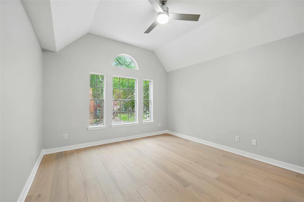 Bright and airy second-floor bedroom featuring large windows, sleek flooring, and a modern ceiling fan.