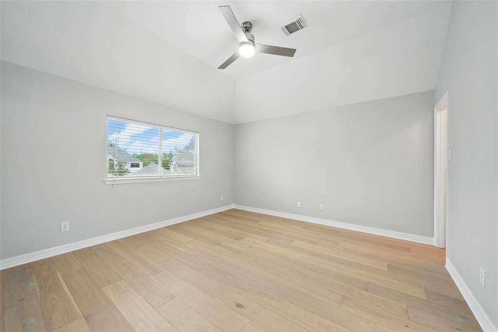 Serene bedroom featuring ample natural light, elegant hardwood floors, and a sleek ceiling fan for added comfort.