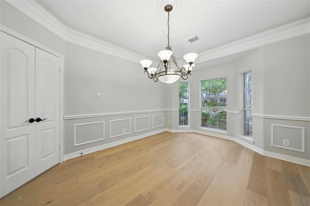 Elegant formal dining room with large windows and a stylish chandelier.