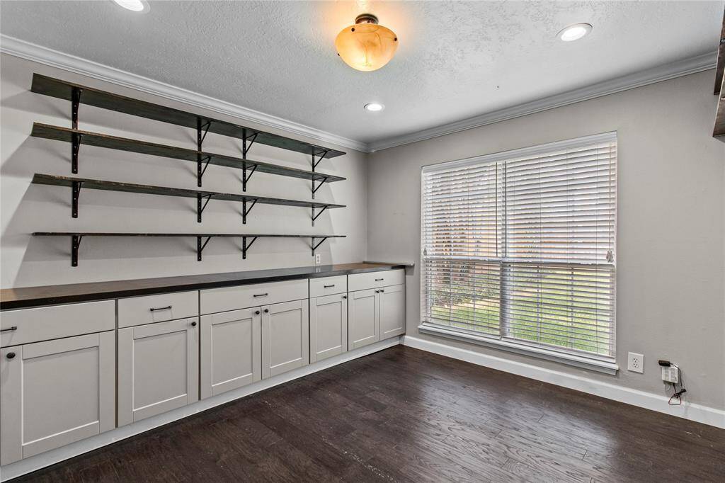 The office is situated to the left of the kitchen and has built in cabinetry and shelving.