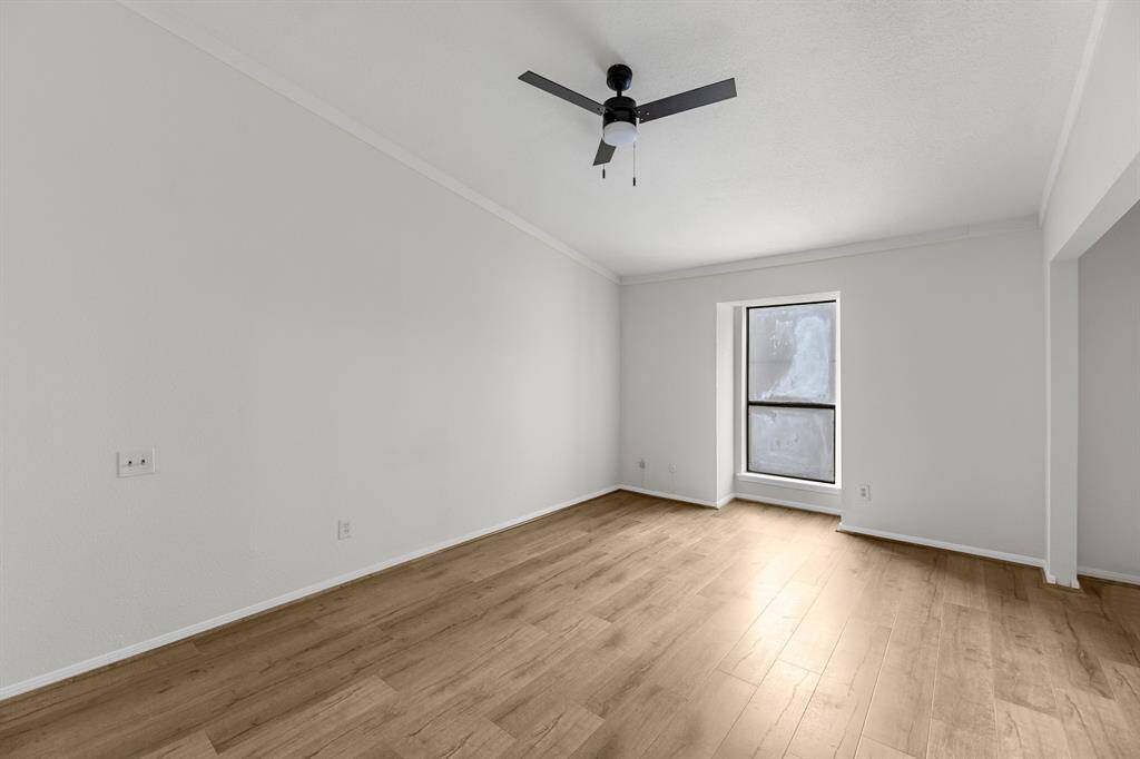 Primary Bedroom features laminate wood flooring, fresh updated walls, and a modern ceiling fan. A large window provides natural light, creating a bright and airy atmosphere.