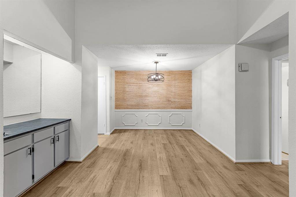 The open dining area features laminate wood flooring, stylish chandelier and a textured accent wall that adds character plus there's a built-in counter with storage on the left, perfect for entertaining.
