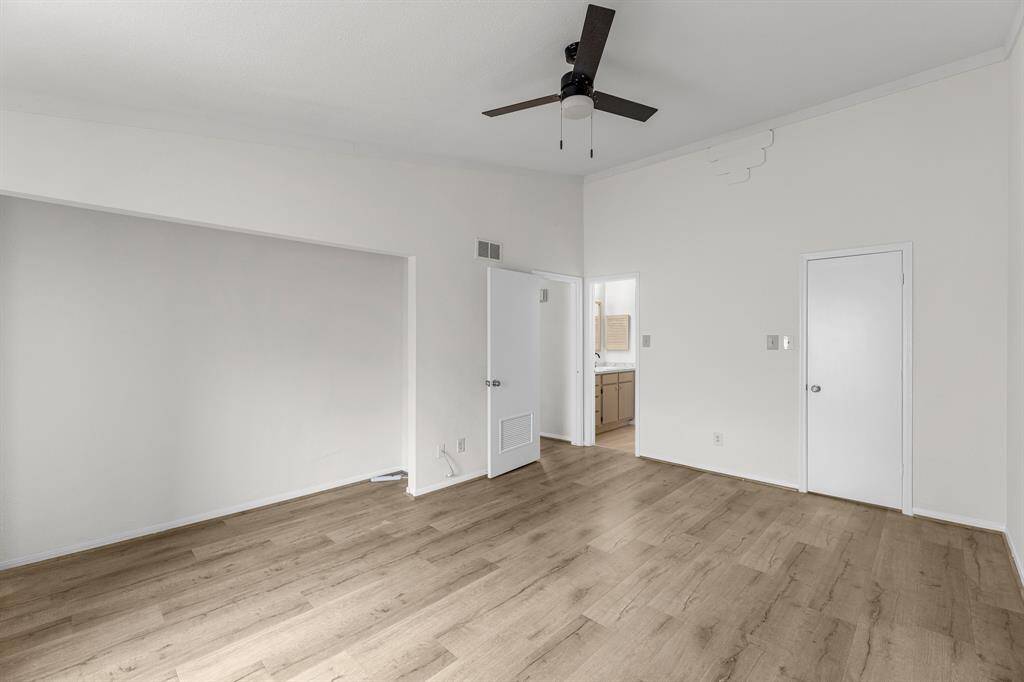 The Primary Bedroom features a minimalist design with laminate wood flooring, neutral walls, a ceiling fan, and ample natural light. It includes a walk-in closet and updated bathroom.