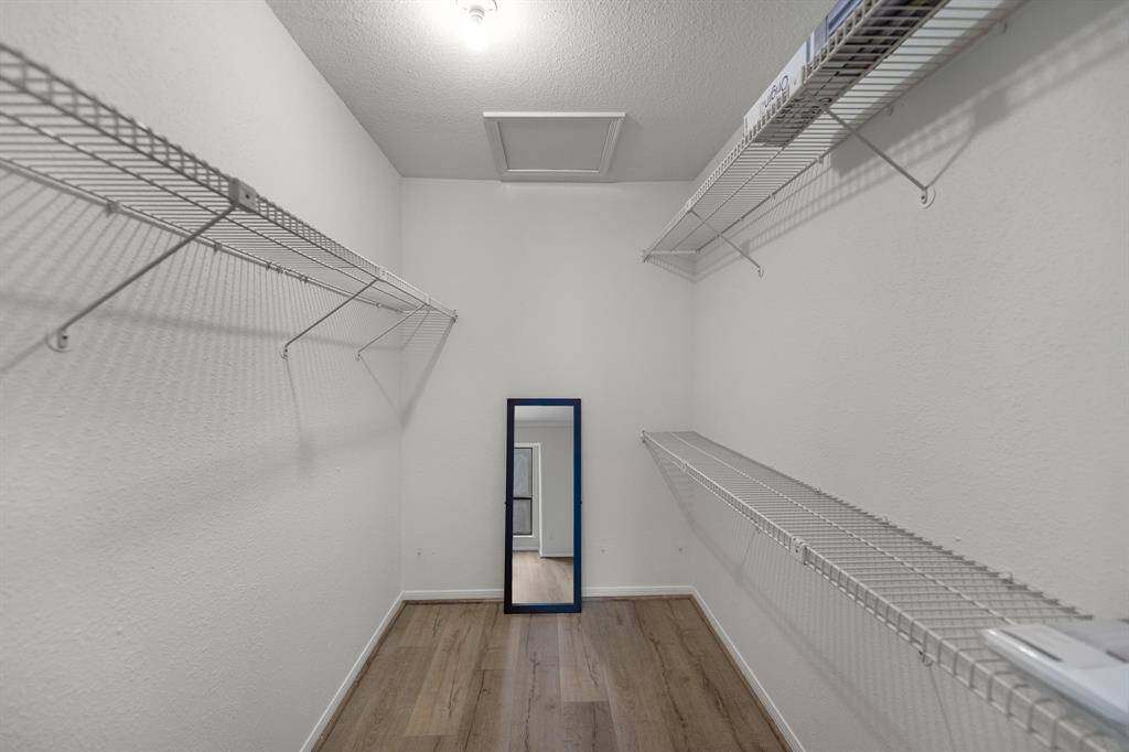 Spacious walk-in closet with white wire shelving on both sides.