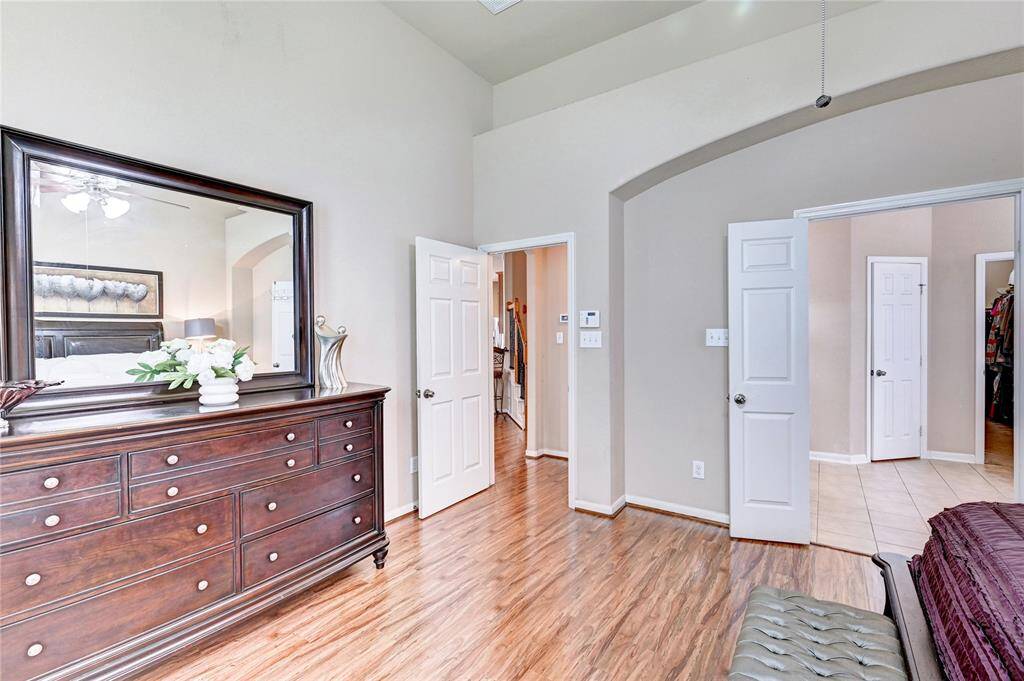 A spacious bedroom with wooden flooring. Arched doorway. Natural light enhances the airy feel.