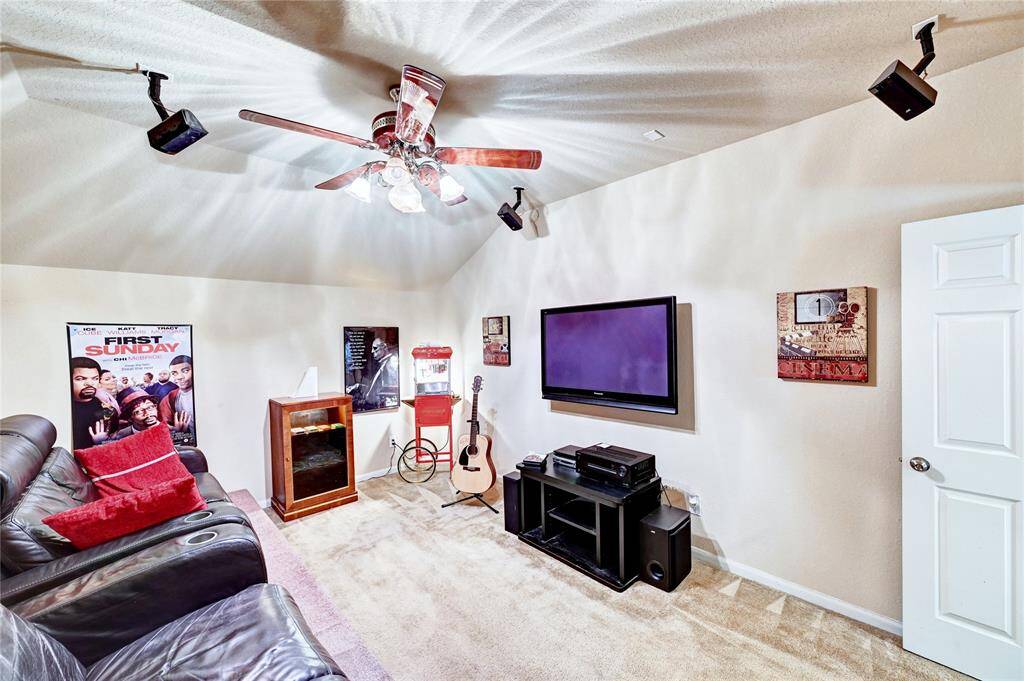 Cozy home theater room with a ceiling fan, wall-mounted TV, and surround sound speakers. Perfect for movie nights and entertainment.