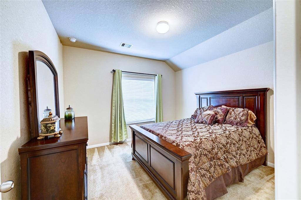 This cozy bedroom features a plush carpet. Natural light filters through a window  creating a warm and inviting atmosphere.