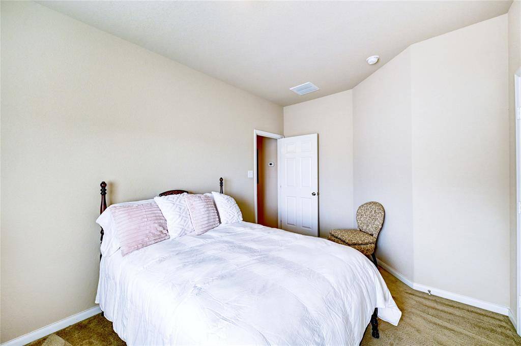 Bright, cozy bedroom with neutral walls, carpeted floor, and a comfortable bed. Ideal for relaxation.