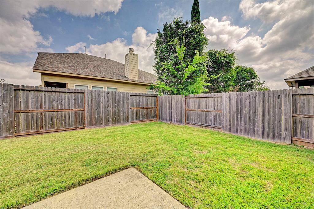 A cozy backyard featuring a well-maintained grassy area, enclosed by a wooden fence. Ideal for outdoor activities or gardening, with a partial view of neighboring houses.