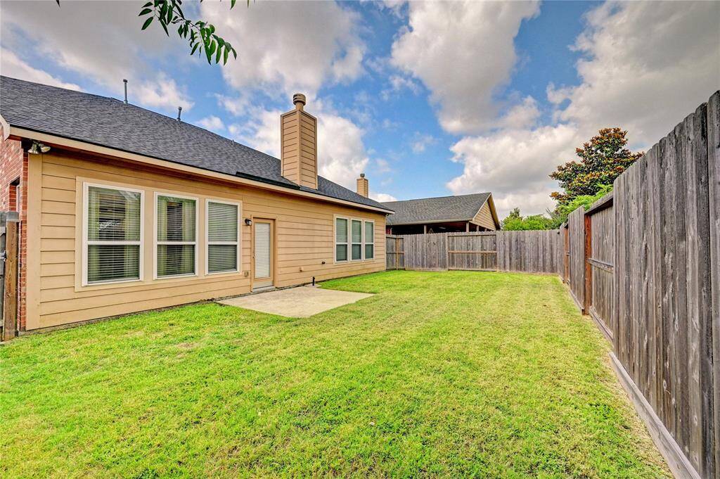 This photo showcases a spacious fenced backyard with a well-maintained lawn, perfect for outdoor activities. The house features a modern exterior with multiple large windows, allowing for ample natural light inside.