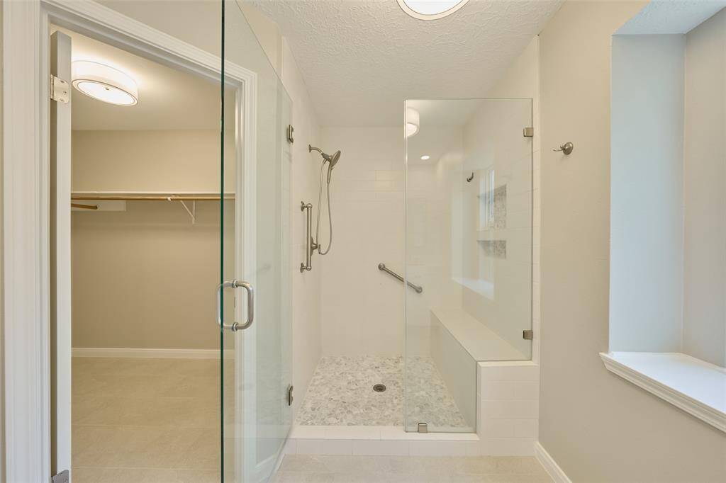 Primary walk in shower with bench and large walk in closet.