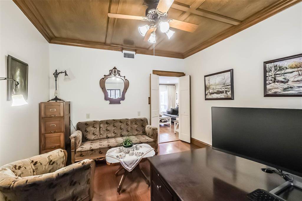 Located behind private Frenchdoors, the room features crown molding, a ceiling fan, and large windows.