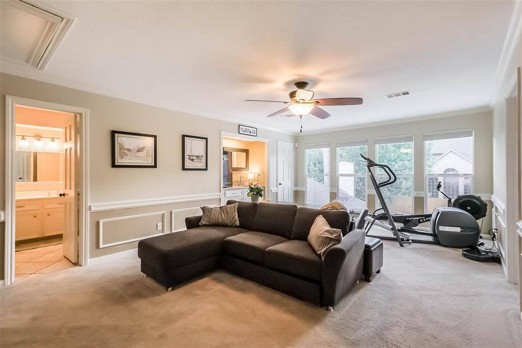 The upstairs game room features plush carpet ceiling fan, and large windows.