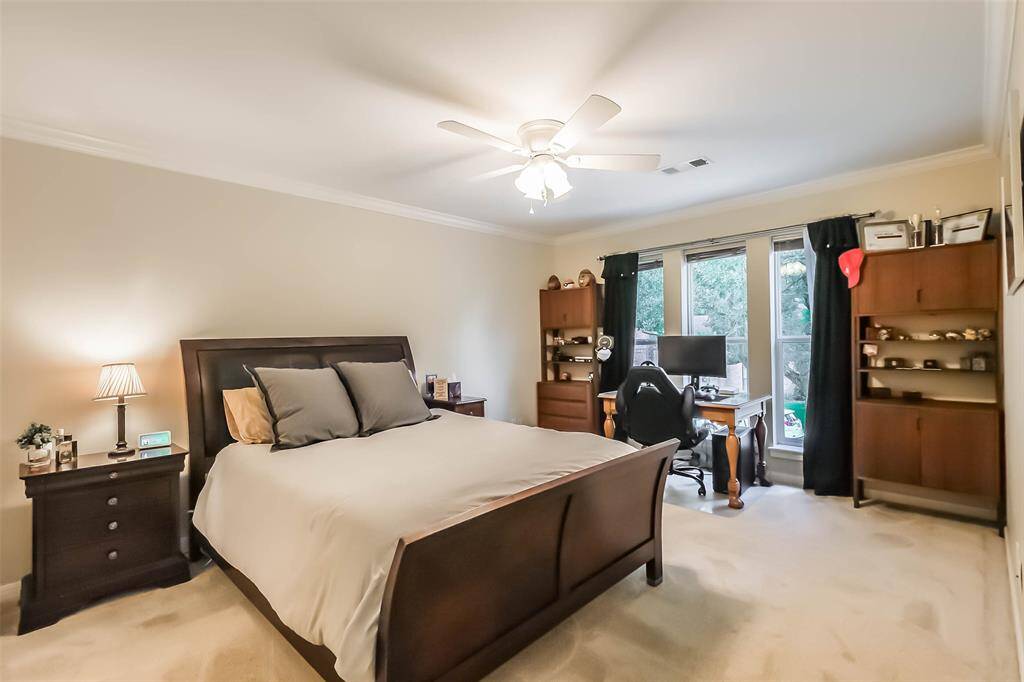Secondary bedroom features largewindows, walk-in closet, crown molding, ceiling fan, and plush carpet.