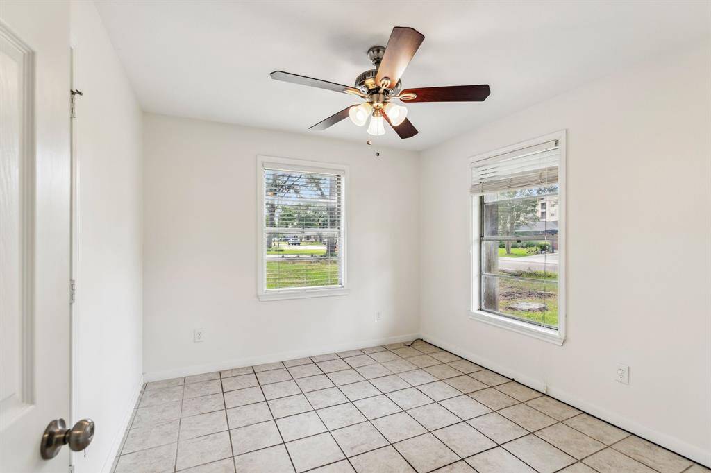 Secondary bedroom #1. This bright and neutral room overlooks the front yard and can easily serve as a guest room, home gym, or secondary office. Dual windows allow soft light to fill the space.