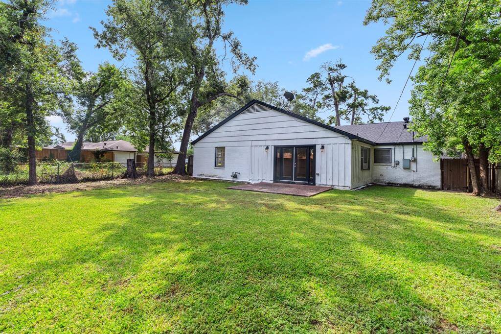 An alternate angle of the backyard highlights its depth and tree-lined perimeter. There’s room to expand, landscape, or simply relax under the Texas sky.