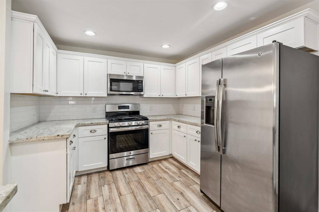 Outfitted with stainless steel appliances and shaker-style cabinetry, the kitchen is both timeless and efficient. Ample countertop space and storage make meal prep a breeze.