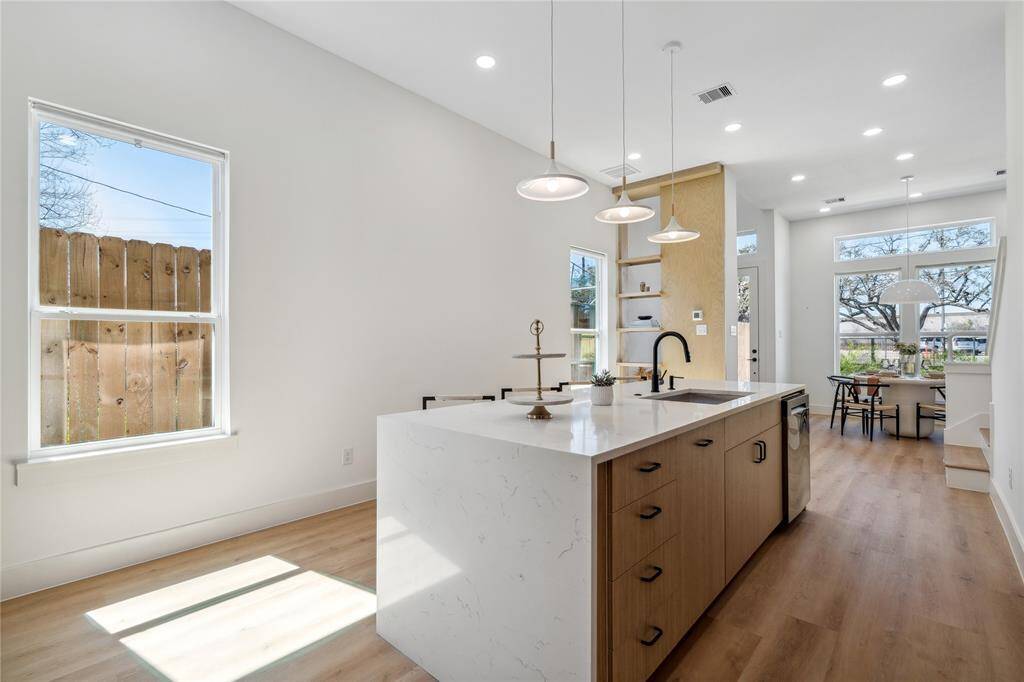 The generous natural light flooding this living, dining, and kitchen space enhances its warm, inviting, and cozy ambiance.