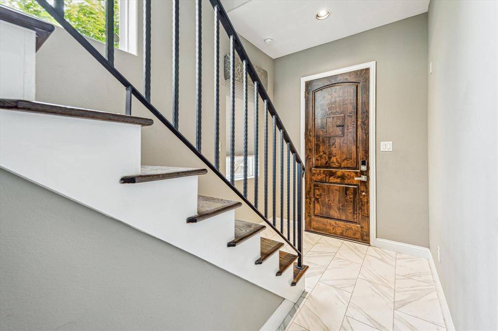 Step inside for a warm welcome with an entryway featuring sleek marble tile flooring, recessed lighting, and a rich, solid wood front door that sets the tone for the rest of the home.