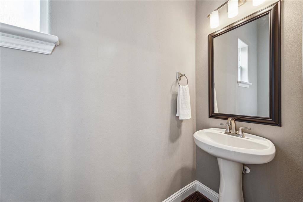 The powder bath is convenient for guests and offers a classic pedestal sink with a framed mirror and stylish vanity lights above.
