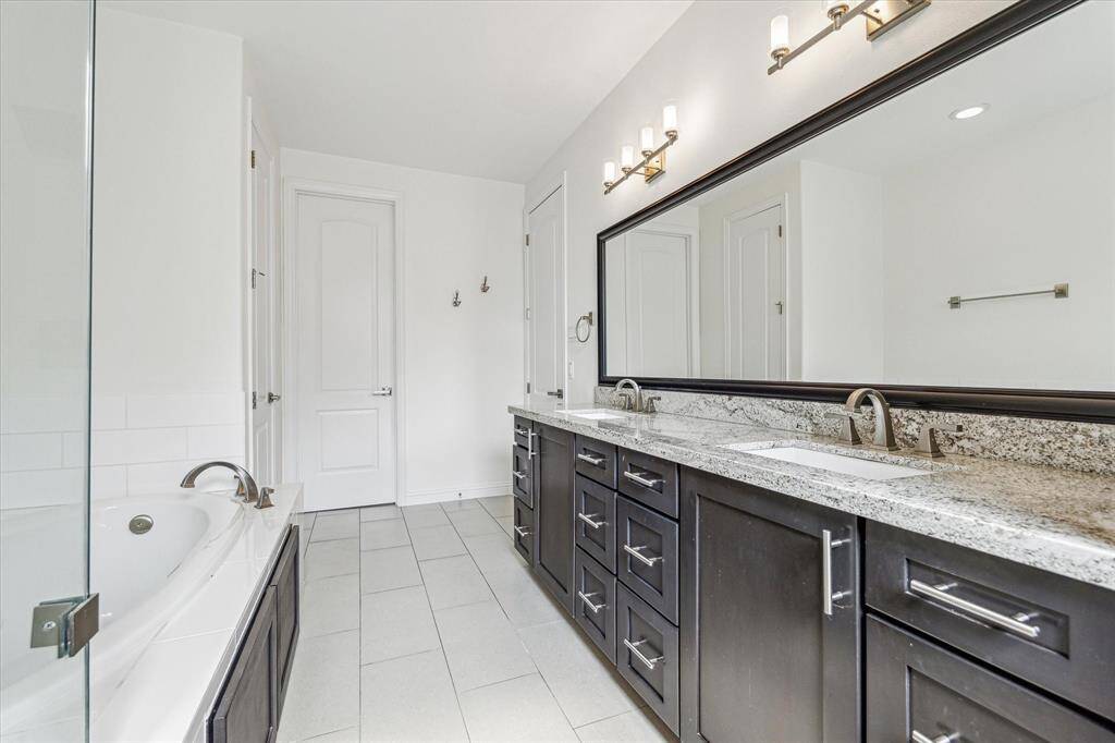With an extended granite vanity featuring dual sinks and ample storage, this ensuite is perfectly designed for sharing. A full-width framed mirror and modern lighting complete the polished, functional layout.