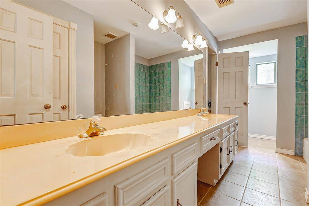 secondary bathroom with dual sinks with a tub/shower combo.