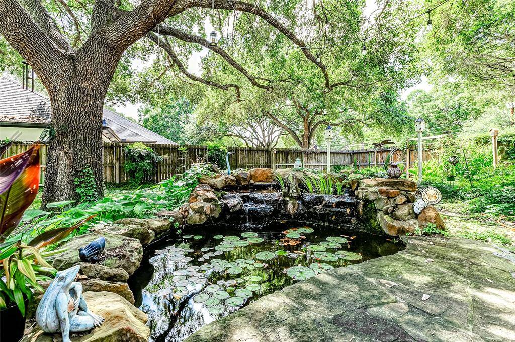 Tree lined backyard with a beautiful pond.