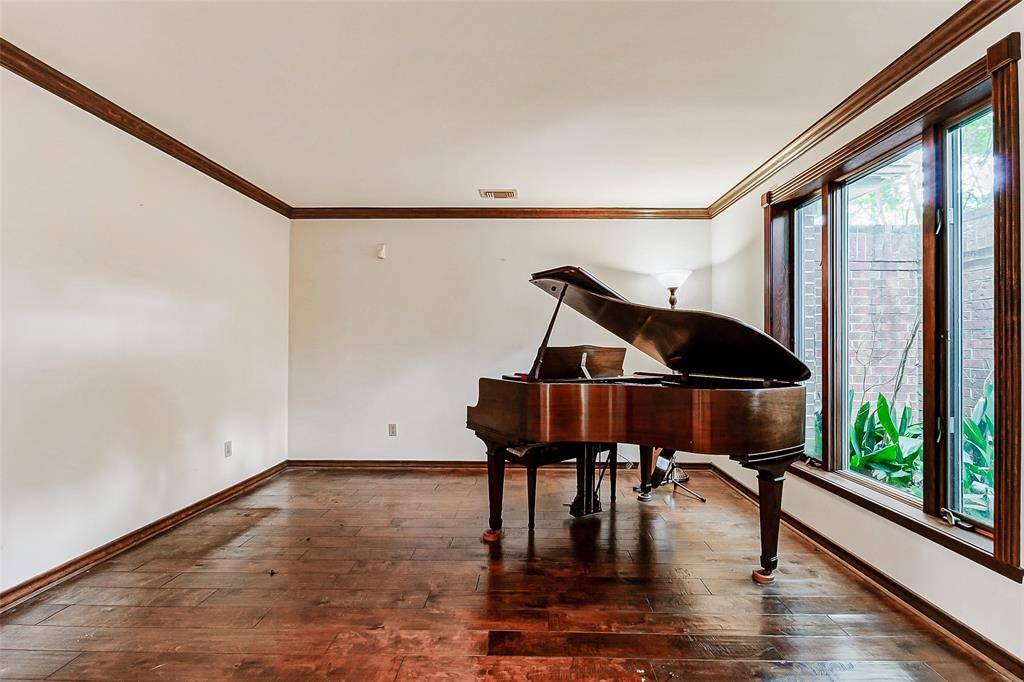Formal living or a music room with hardwood floors and expansive windows.