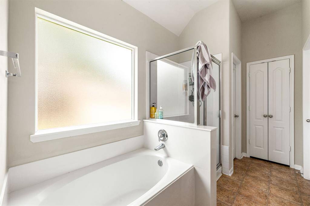 This additional view of the primary bath showcases a walk-in shower with tile surround and a separate garden tub perfect for soaking after a long day.