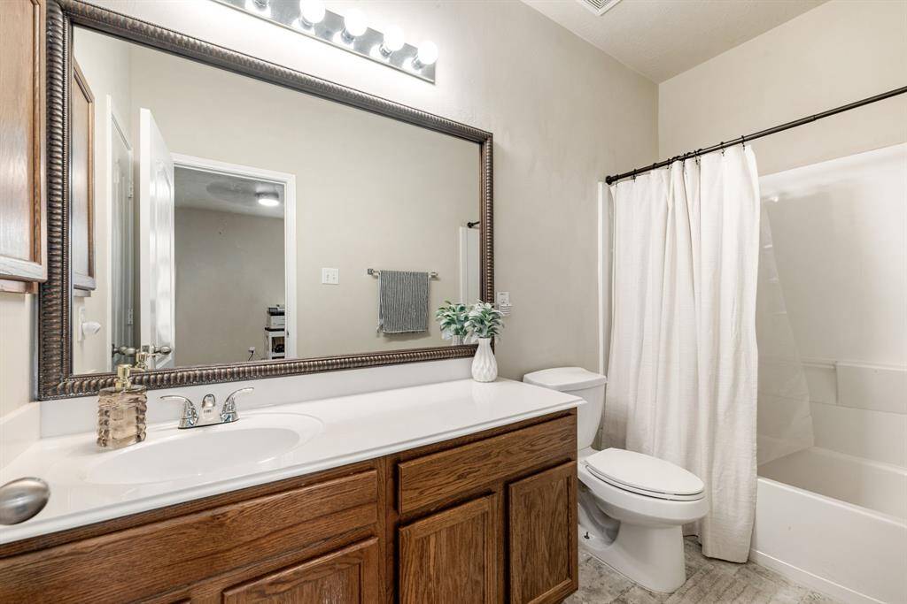 Secondary bathroom features light countertops and cabinets, custom paint, shower/tub combo with tile surround, large mirror, tile floors, sleek fixtures and modern finishes, plenty of space to accommodate any visiting family or guests.
