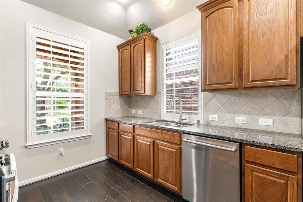 Sun-filled kitchen enjoys a picture-window view of the front yard, with a deep stainless-steel sink and matching dishwasher set into gleaming countertops for effortless prep and clean-up.