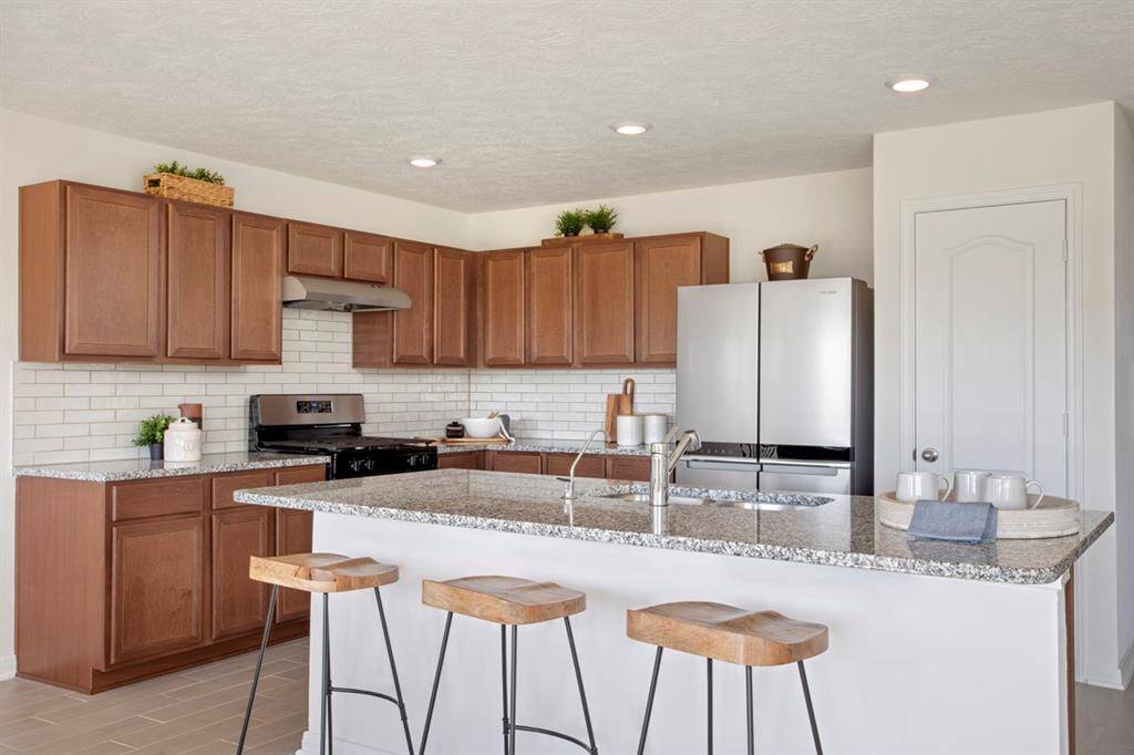 This kitchen is by far any chef’s dream! This spacious kitchen features a beautiful island, high ceilings, recessed lighting, Woodmont Cody cabinets in Ginger stain, SS appliances, modern tile backsplash, and a walk-in pantry all overlooking your huge family room!