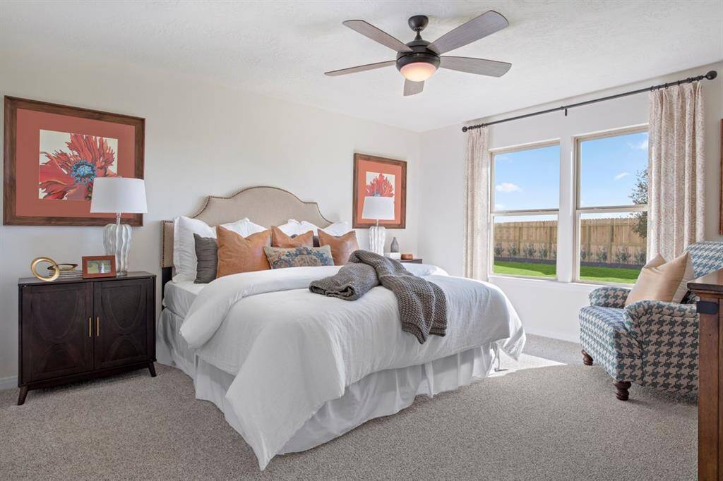 What a wonderful place to come home to, this stunning primary suite greets you with plush carpet flooring, warm custom paint, high ceiling, ceiling fan with lighting, and large windows with window covering with a gorgeous view of the backyard.