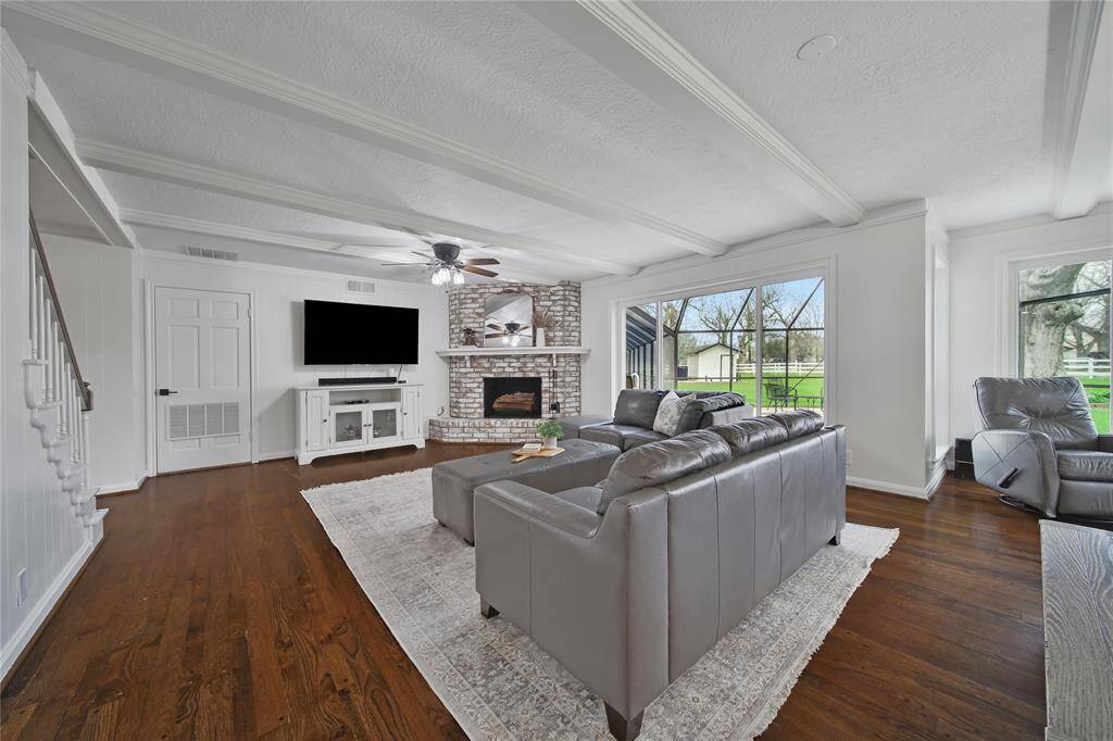 The living room exudes a warm and inviting atmosphere, making it the perfect space for friends and family to gather. The custom wood-burning fireplace with its painted wood mantle serves as a striking decorative focal point, enhancing the room's cozy charm.