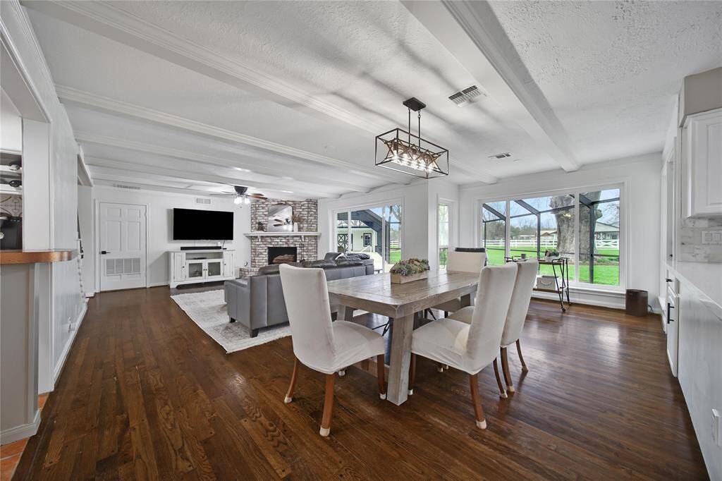 The row of farmhouse-style windows fills the space with natural light, creating a bright and inviting atmosphere. They also offer perfect sightlines into the backyard, showcasing both the pool and the lush grassy areas. The area by the windows is situated to create a cozy spot in the sun while reading or enjoying a cup of tea.