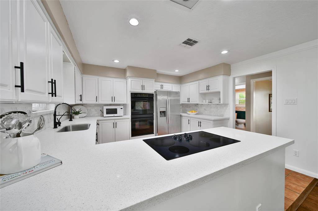 Another angle of this updated kitchen. The unique design of the room maximizes counter space while maintaining a great sense of flow whenever it comes time to prepare a meal for the family. The door way to the right leads to both an open, walk through pantry (plus a 2nd closed one) and gives easy access to serve the formal Dining Room.